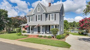 A two-story house with a front porch, a chimney, and a flagpole with an American flag. - Historic Waterfront Home w/ Dock in Reedville! (Reedville)