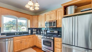 A modern kitchen with wooden cabinets, stainless steel appliances, and a large window providing natural light. - Historic Waterfront Home w/ Dock in Reedville! (Reedville)
