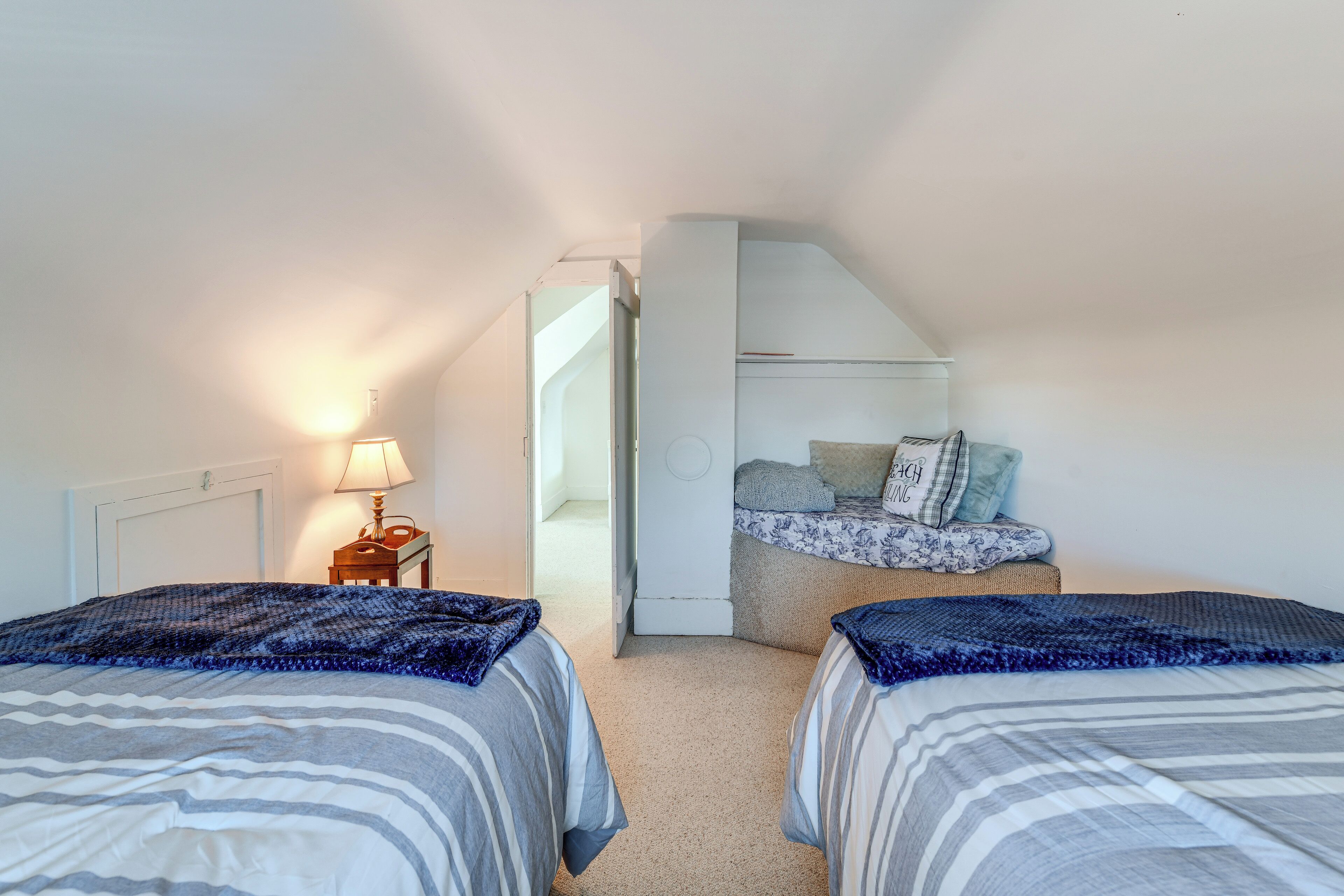 A bedroom with two beds, a nightstand, and a dresser.