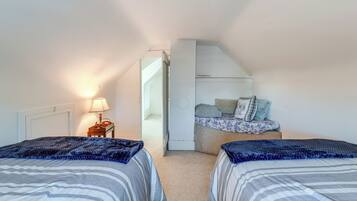A bedroom with two beds, a nightstand, and a dresser.