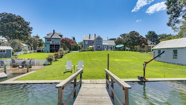 A wooden dock leading to a grassy area with a house in the background. - Historic Waterfront Home w/ Dock in Reedville! (Reedville)