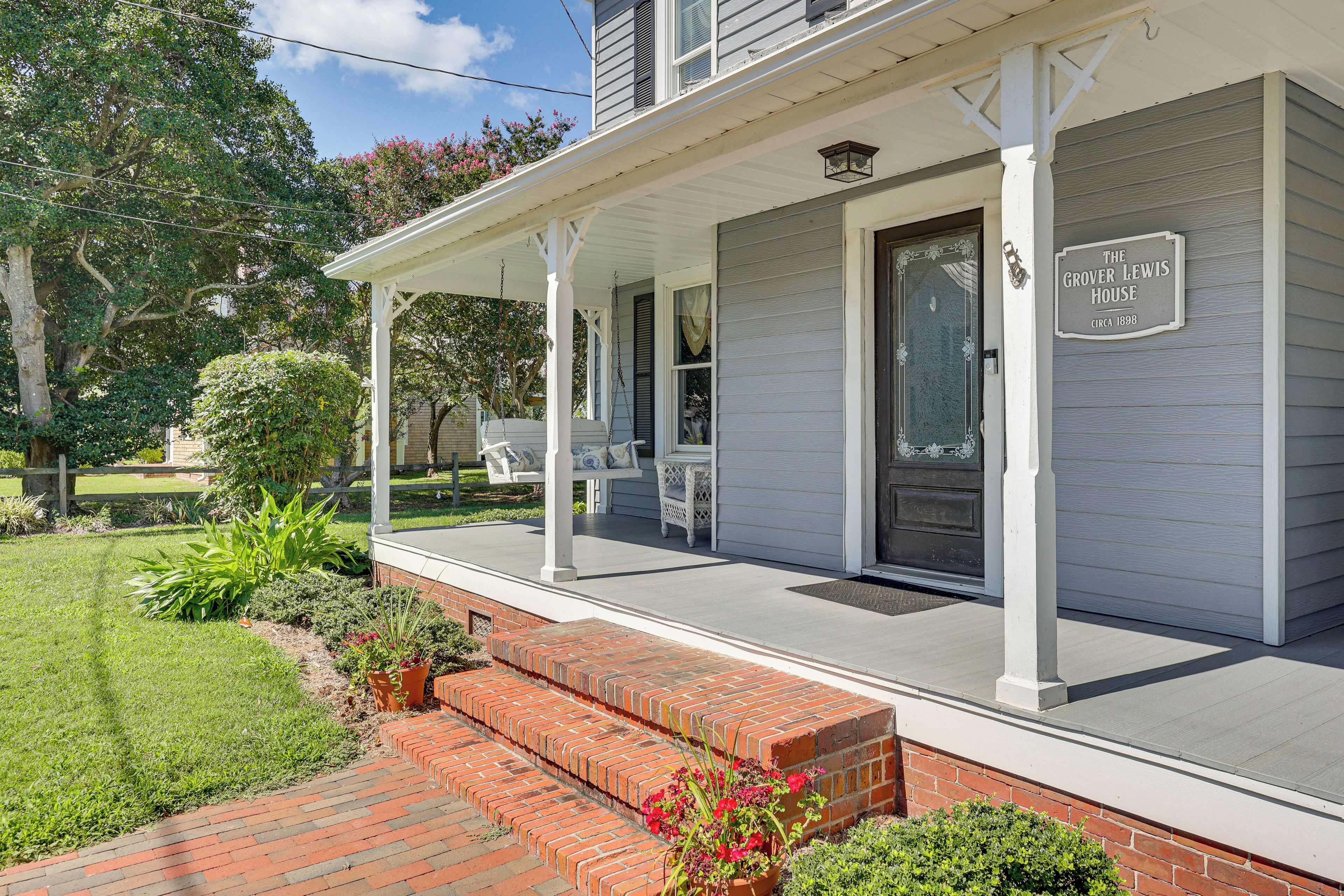 A house with a porch, a brick entrance, and a sign that reads "The Grover Lewis House circa 1898".
