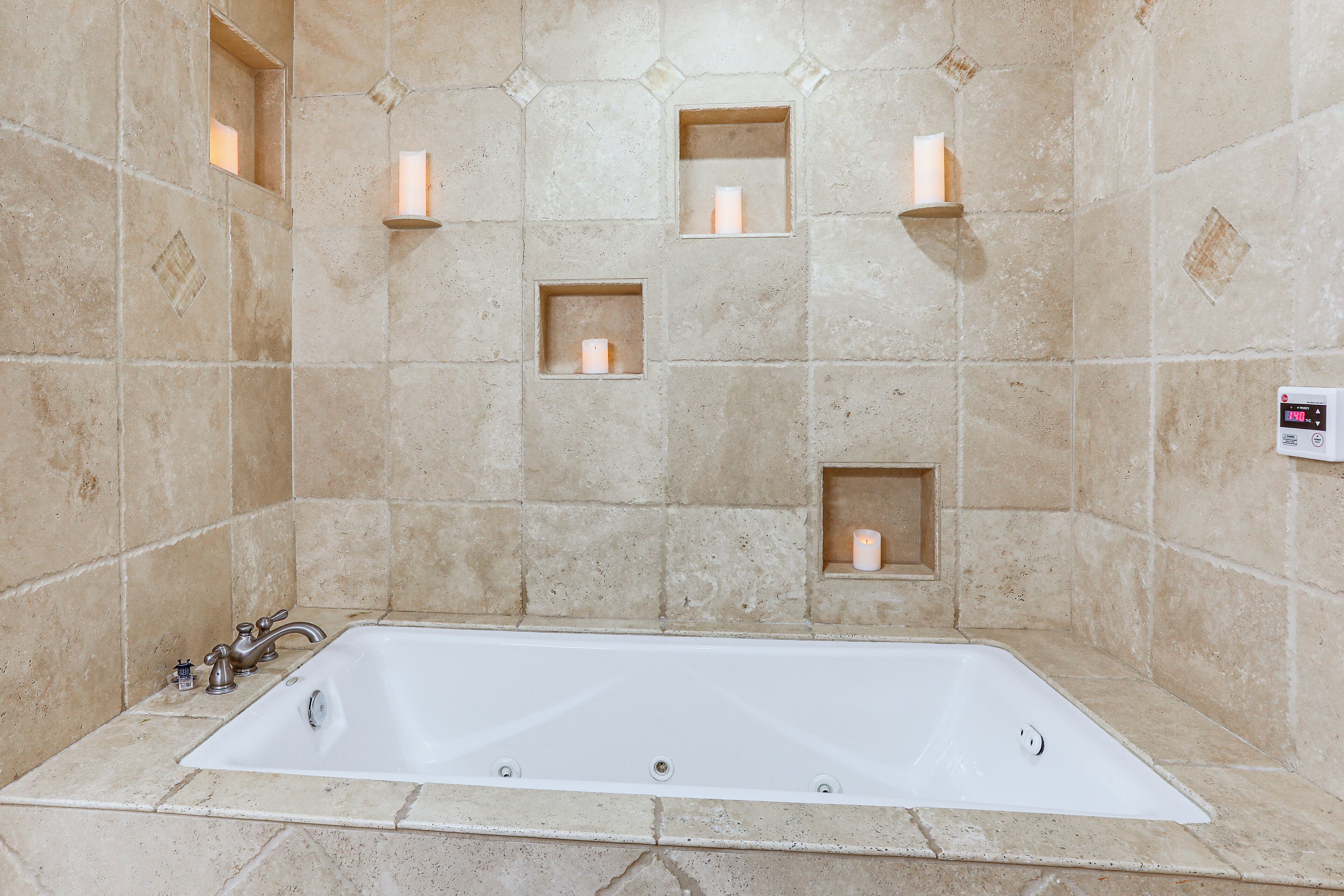 A bathroom with a bathtub, tiled walls, and recessed lighting.