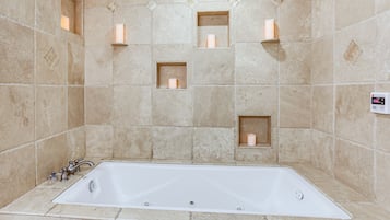 A bathroom with a bathtub, tiled walls, and recessed lighting.
