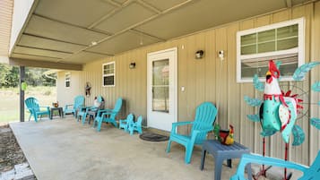 A covered patio area with turquoise chairs and a decorative rooster statue.