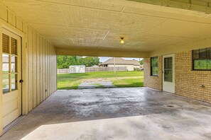 Un patio couvert avec un sol en béton, une porte en bois et un mur en briques.