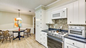 A kitchen with white cabinets, a microwave, a stove, and a dining area with a table and chairs. - Healthcare-worker Hub 2 Mi to Texarkana Hospitals! (Texarkana)