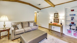 A living room with a sofa, ottoman, wooden table, and bookshelf. - Healthcare-worker Hub 2 Mi to Texarkana Hospitals! (Texarkana)