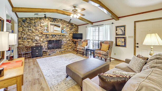 A cozy living room with a stone fireplace, wooden beams, a ceiling fan, and a comfortable seating area. - Healthcare-worker Hub 2 Mi to Texarkana Hospitals! (Texarkana)