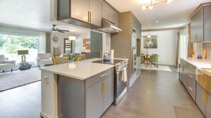 A modern kitchen with a central island, built-in appliances, and a dining area with a view. - Modern Creekside Retreat 1 Mi to Spirit Mtn Casino (Grand Ronde)