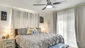 A bedroom with a bed, bedside tables, a ceiling fan, and a window with curtains. - Modern Creekside Retreat 1 Mi to Spirit Mtn Casino (Grand Ronde)