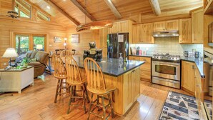 A spacious kitchen with wooden cabinets, a central island with bar stools, a large refrigerator, and an oven. - Luxe Mountain Escape w/ Hot Tub & Gym Near Boone! (Zionville)