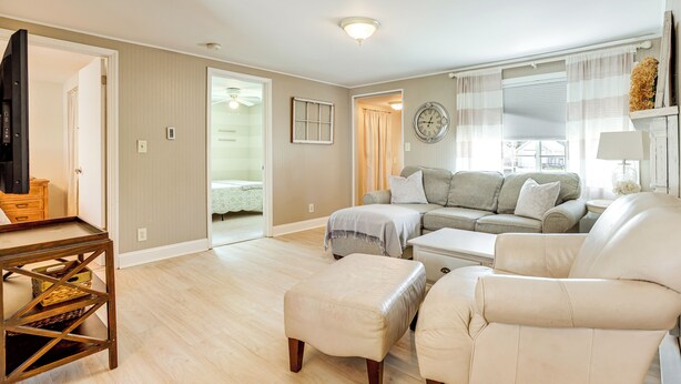 A spacious living room with a large sofa, ottoman, and a television on a wooden stand.