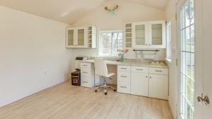 A spacious kitchen with white cabinets, a built-in oven, and a window with a view of the outdoors.