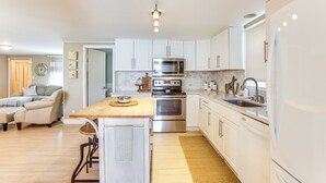A modern kitchen with white cabinets, stainless steel appliances, and a wooden island.
