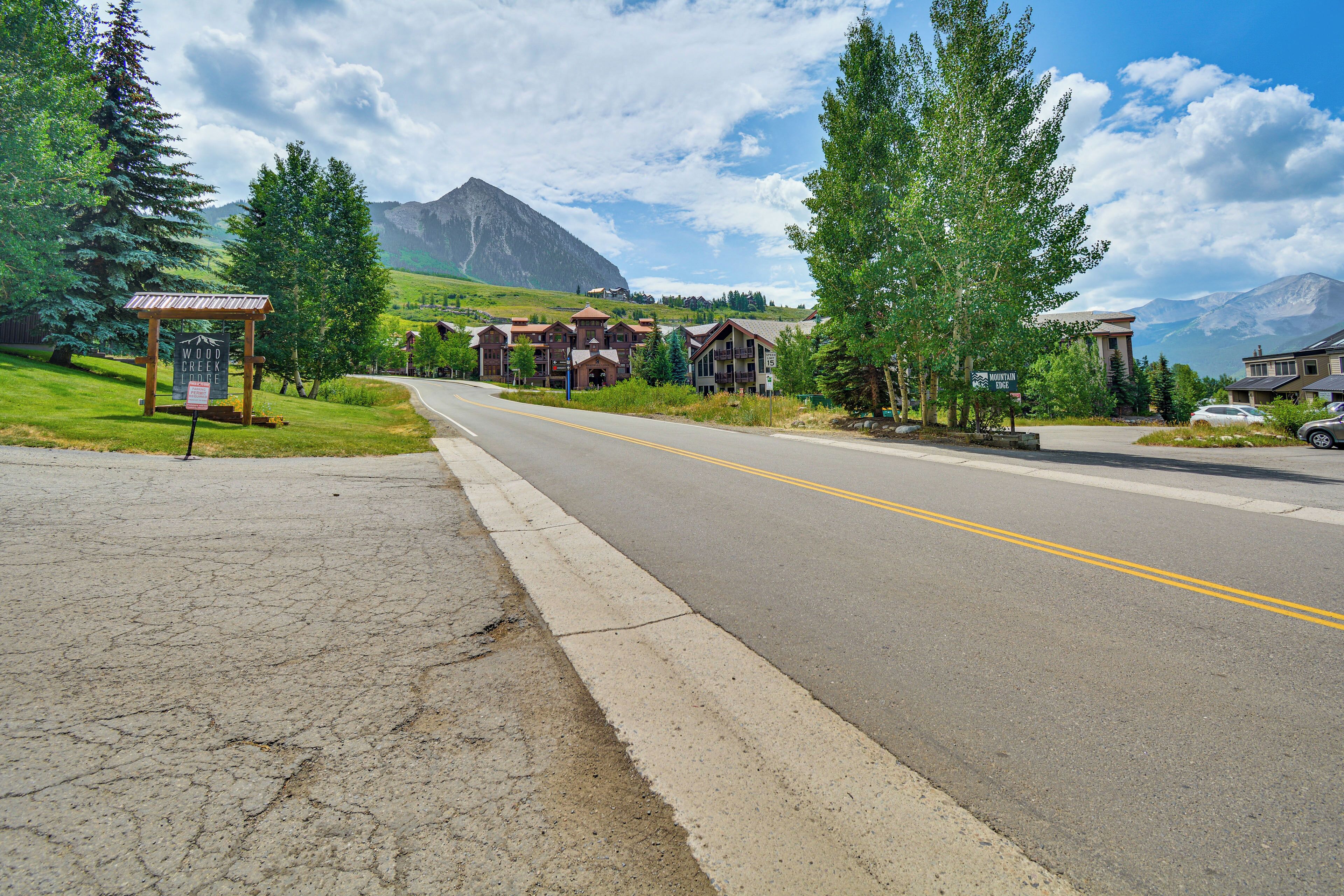 A road leading to a row of wooden buildings with a mountain in the background.