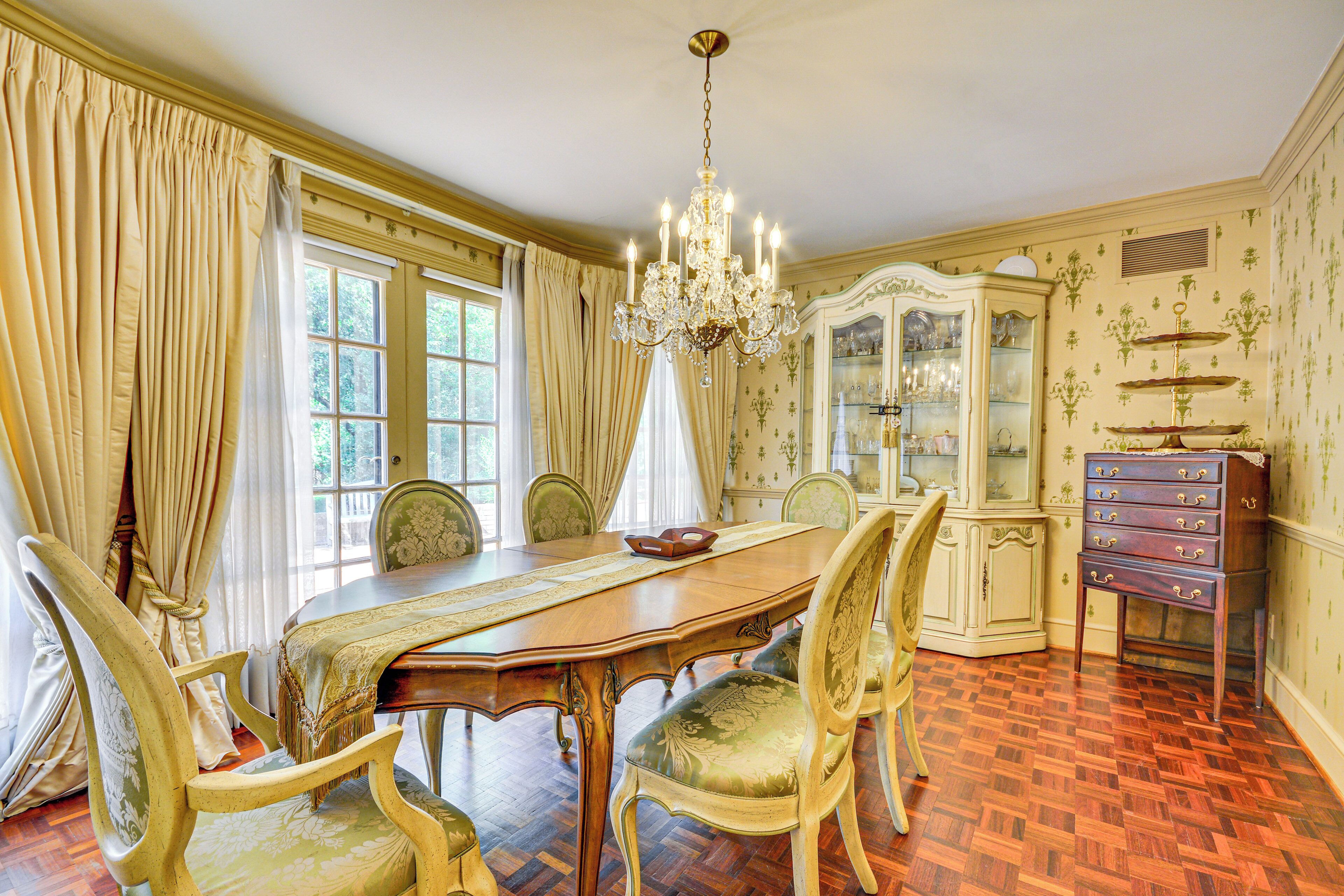 A formal dining room with a wooden table, ornate chairs, a chandelier, and a glass cabinet with decorative items.