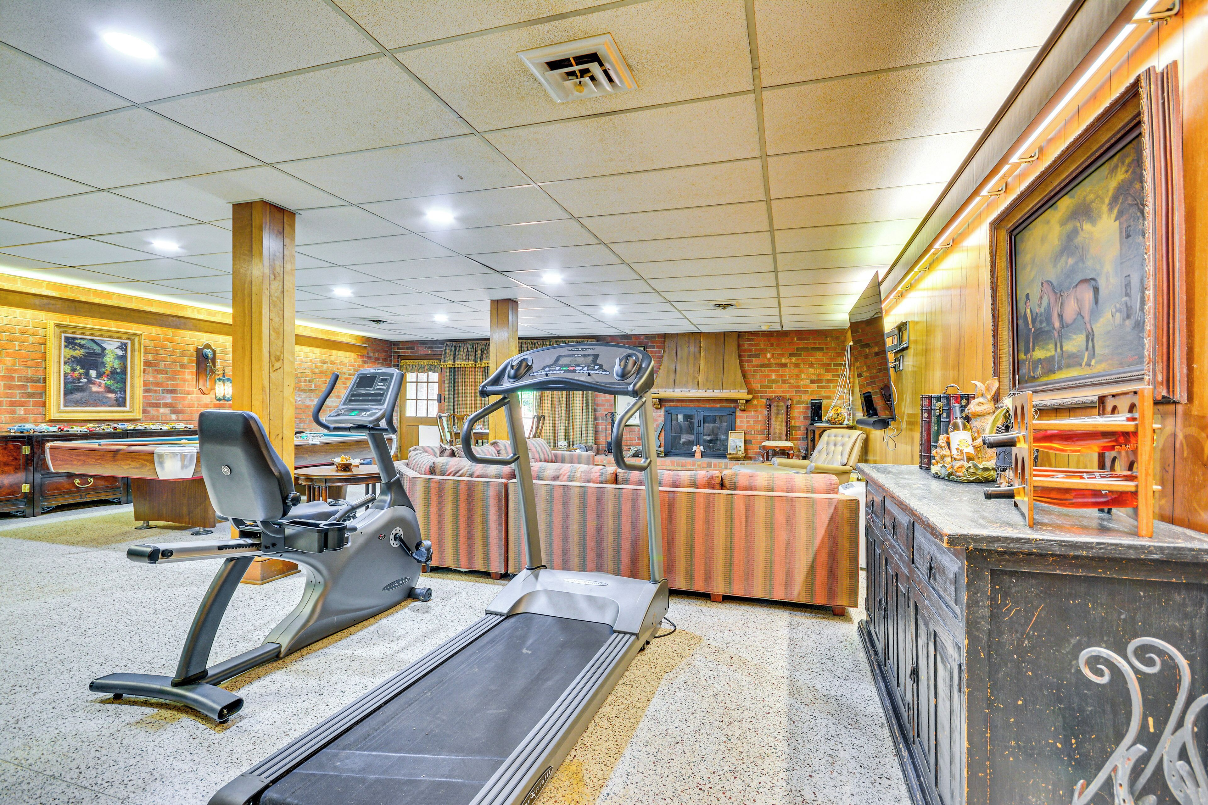 A gym with treadmills, a stationary bike, and a pool table.