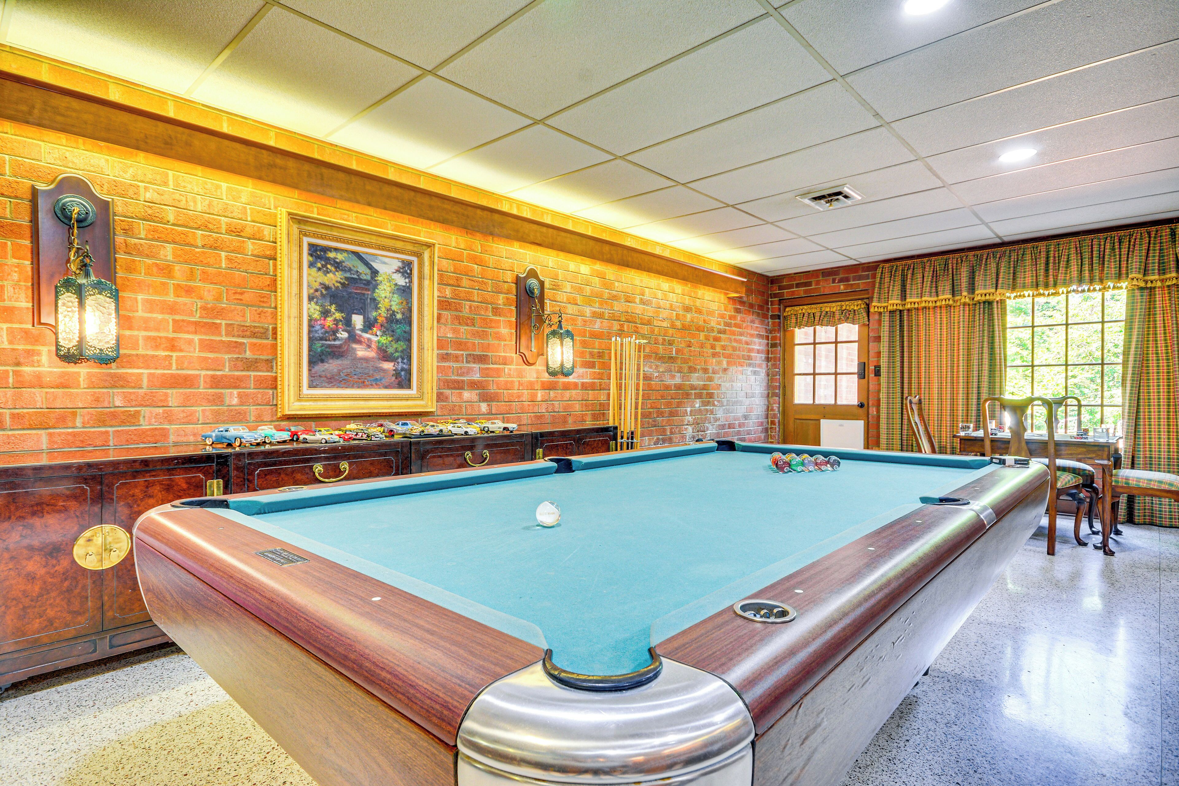 Une table de billard avec un cadre en bois et un drap de jeu bleu, entourée de murs en briques et de meubles en bois.