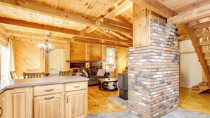 A wooden interior with a kitchen area, a fireplace, and a dining space. - 7 Mi to Glens Falls: Peaceful Retreat w/ Game Room (Hudson Falls)