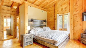 A wooden cabin bedroom with a bed, nightstand, and dresser. - 7 Mi to Glens Falls: Peaceful Retreat w/ Game Room (Hudson Falls)
