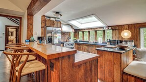 A kitchen with wooden cabinetry, a central island with stools, a skylight, and a view of the outdoors. - 15 Mi to Long Island Sound: Bedford Winter Retreat (Bedford)