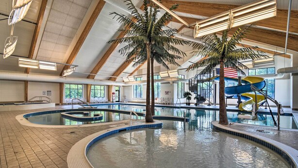 An indoor swimming pool with multiple lanes, palm trees, and a water slide. - Cabin Near Lake w/ Deck, Fire Pit & Grill! (Elmira)