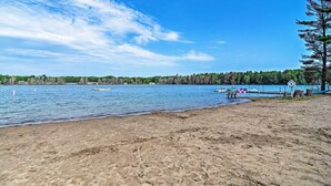 A beach with a clear view of the water, a dock, and a forested area in the background. - Cabin Near Lake w/ Deck, Fire Pit & Grill! (Elmira)