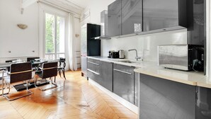 Een moderne keuken met een eethoek, met een groot raam, roestvrijstalen apparatuur en een visgraat parketvloer.