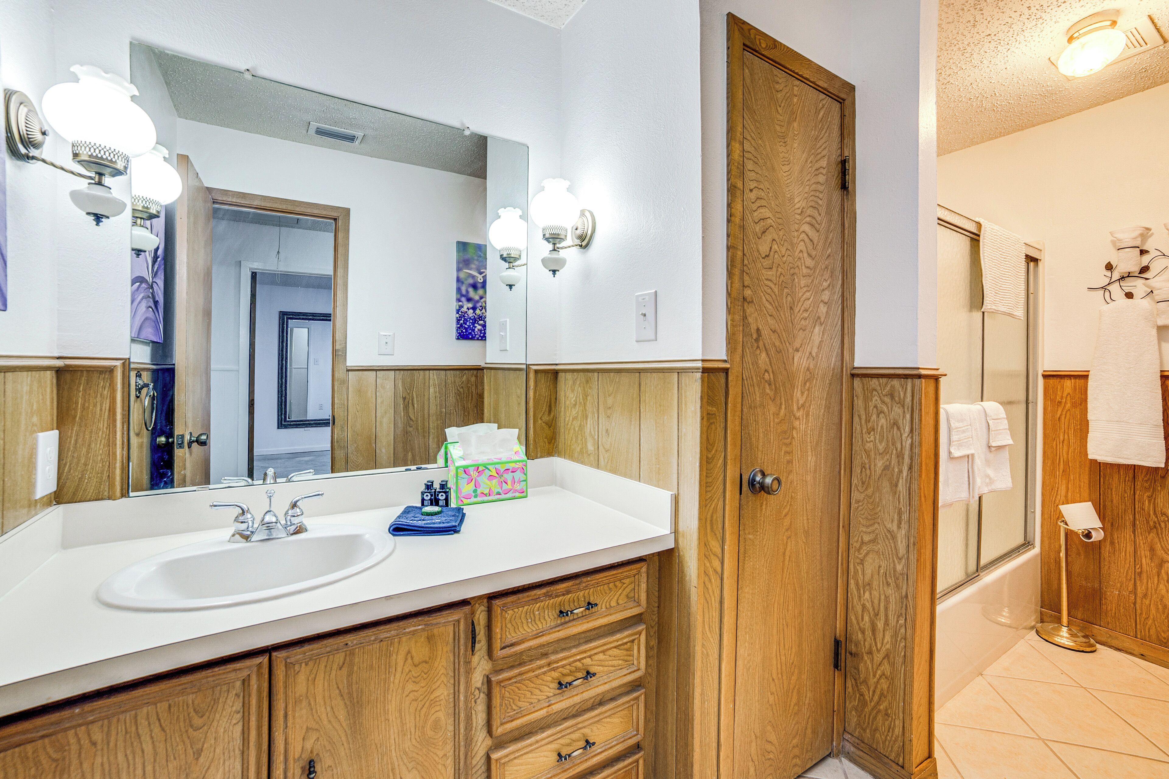A bathroom with a wooden vanity, a large mirror, and a shower area.