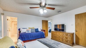 Un dormitorio con cama, cómoda, televisor y ventilador de techo.