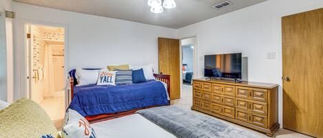 Ein Schlafzimmer mit Bett, Kommode, Fernseher und Deckenventilator.