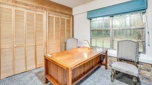 Un salón de conferencias con una mesa de madera, sillas y un amplio ventanal con persianas.