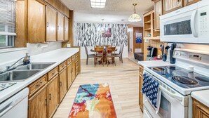 Una cocina con armarios de madera, un microondas, una estufa y una zona de comedor con mesa y sillas.