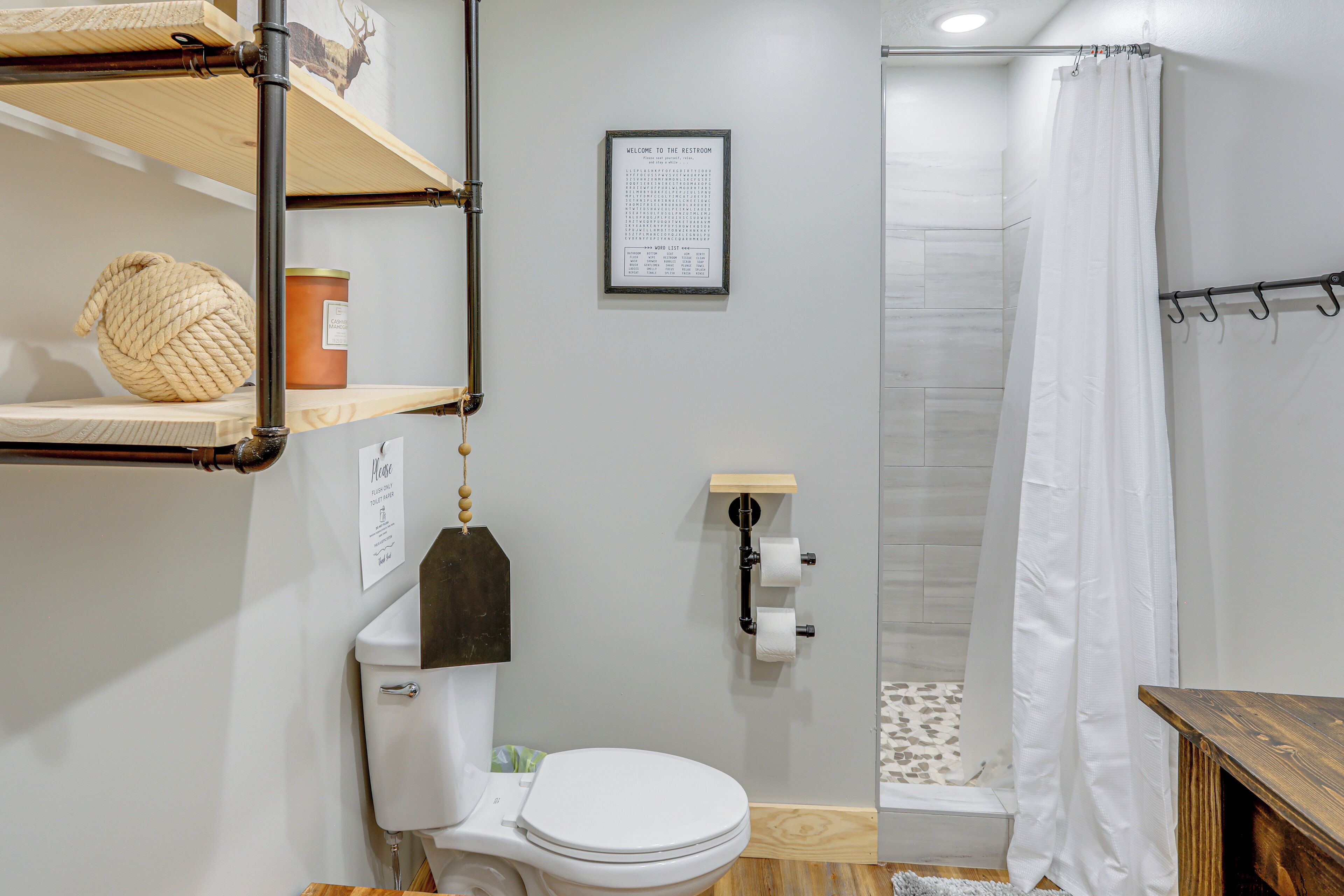 A bathroom with a toilet, a shower curtain, and a sign indicating the restroom.