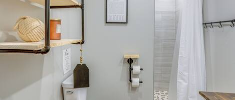 A bathroom with a toilet, a shower curtain, and a sign indicating the restroom.
