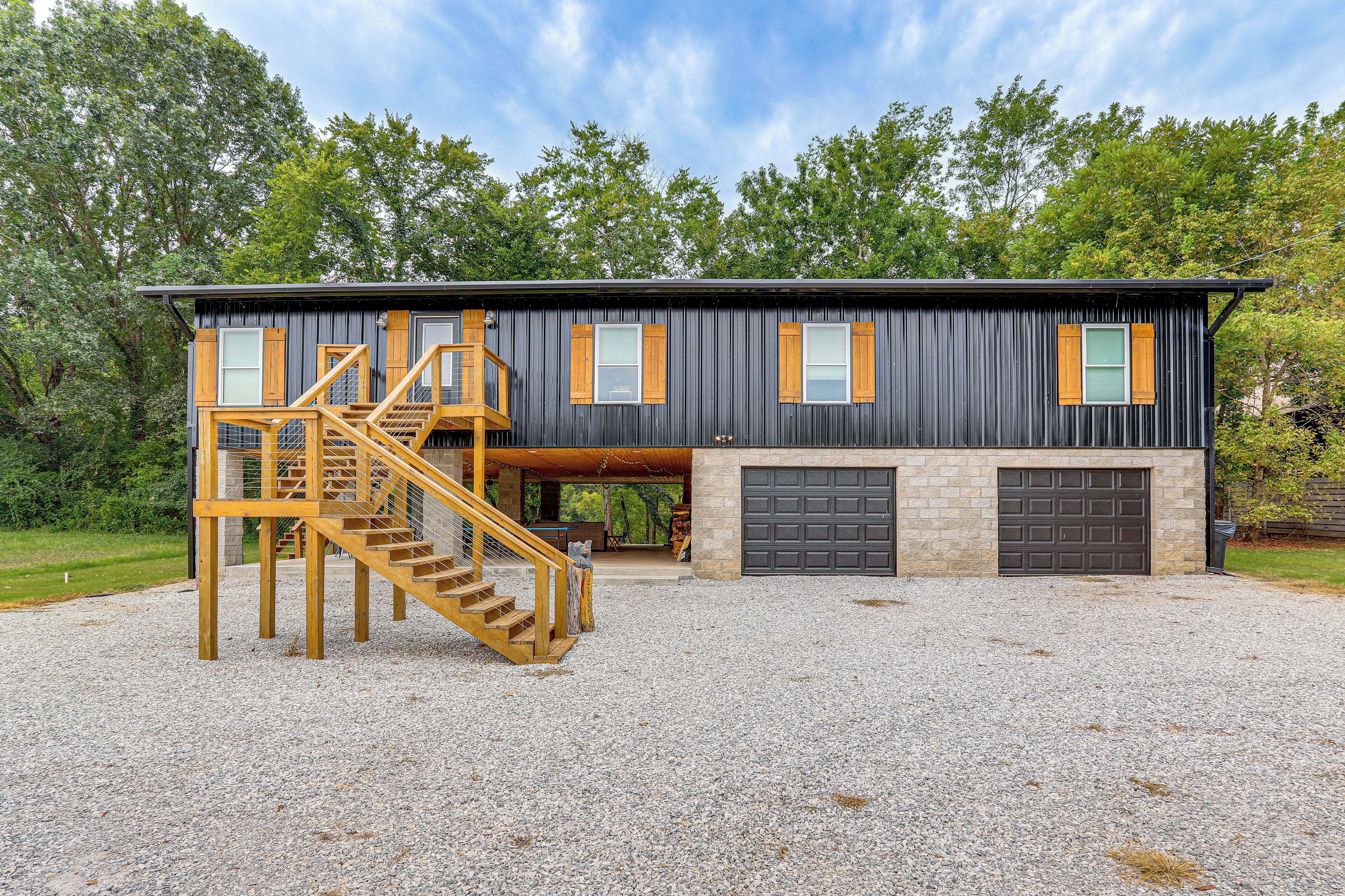A modern two-story house with a gravel driveway, wooden staircase, and a garage.