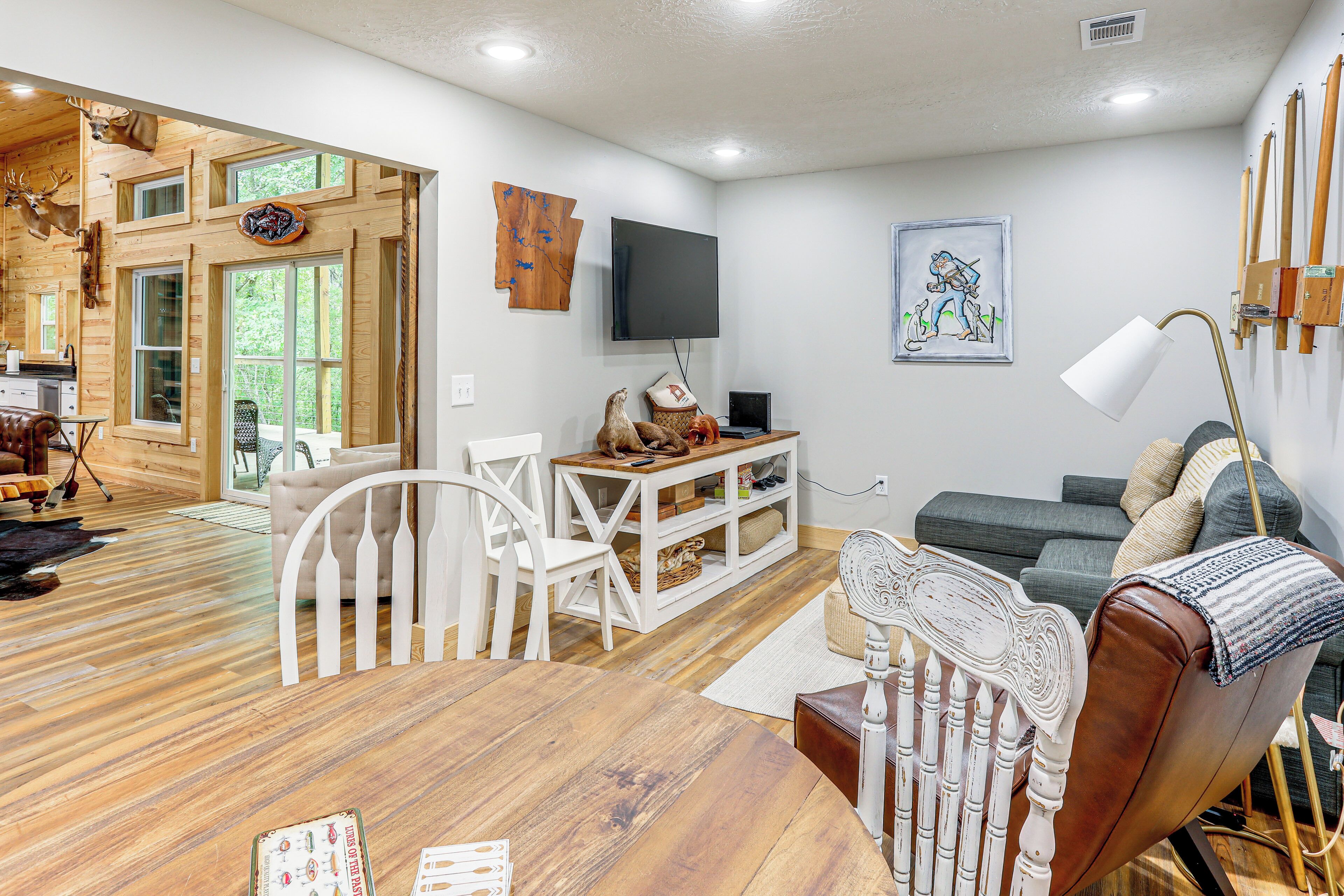 A spacious living area with a wooden floor, a dining table, a sofa, and a TV mounted on the wall.