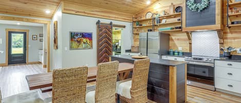 Una cocina moderna con una isla central, electrodomésticos integrados y un comedor con sillas de mimbre.