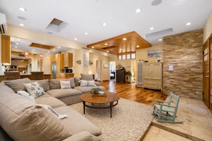 A spacious living area with a large sofa, a coffee table, and a stone accent wall. - Walk 2 SAND Kid Yard, King+Jacuzzi+Bike+Fire Pit (San Diego)