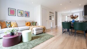 A modern living room with a sofa, ottoman, and a dining area with chairs.