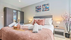 Ein modernes Schlafzimmer mit einem großen Bett, einem Kleiderschrank, einem Nachttisch und einer Topfpflanze.