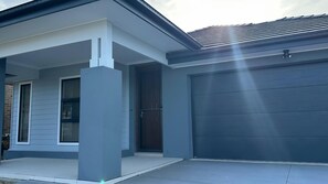 A modern two-story house with a garage door, a front porch, and a brick foundation. - Huntlee Heights | {et Friendly with Fire Pit (North Rothbury)