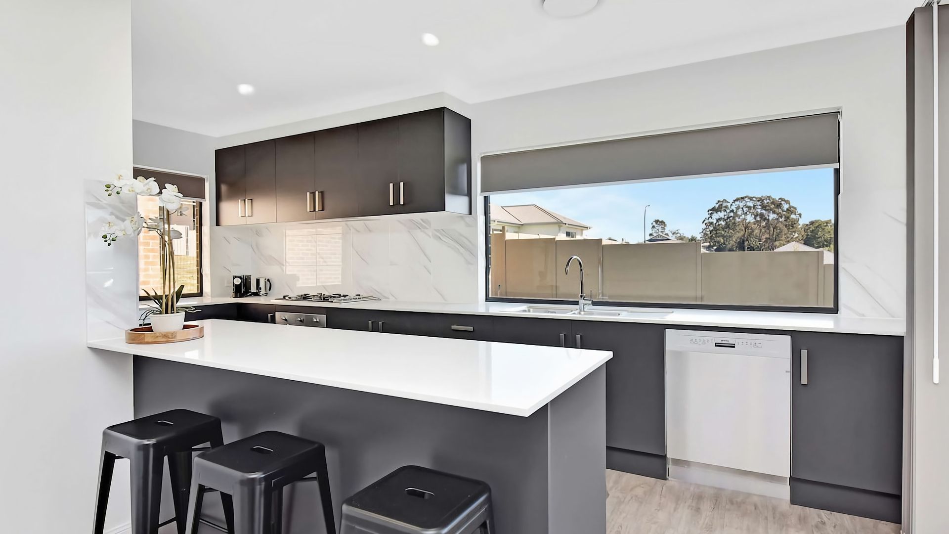 A modern kitchen with a central island, bar stools, and a view of the outside.