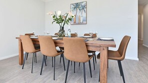 A dining area with a wooden table, six chairs, and a vase with flowers.