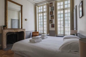 A hotel room with a large bed, a fireplace, and a large window with multiple panes. - Exceptional apt - 2br/4p- Notre-dame Cathedral (Paris)