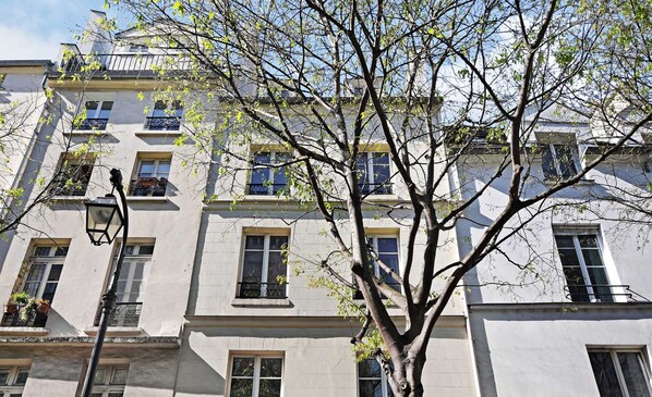 A multi-story building with balconies, windows, and a tree in front. - Le Marais - Rue de Bretagne (Paris)