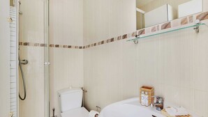 Un bagno con cabina doccia in vetro, un water e un lavabo con articoli da toilette.