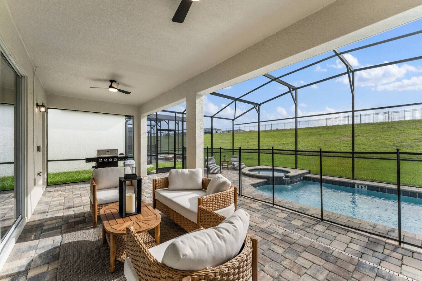 Un espacio al aire libre cubierto con piscina, mobiliario de mimbre y una parrilla.