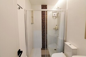 A modern bathroom with a glass-enclosed shower, a white toilet, and a tiled backsplash.